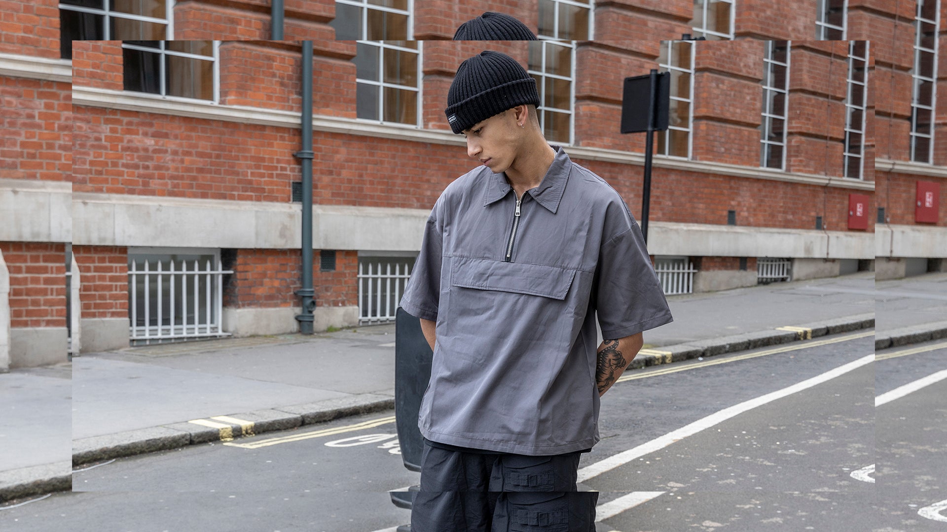 A male model wearing black cargo pants is posing on the street.