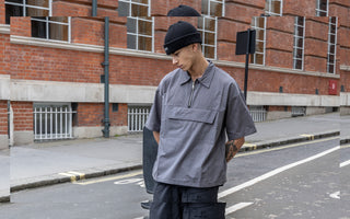 A male model wearing black cargo pants is posing on the street.
